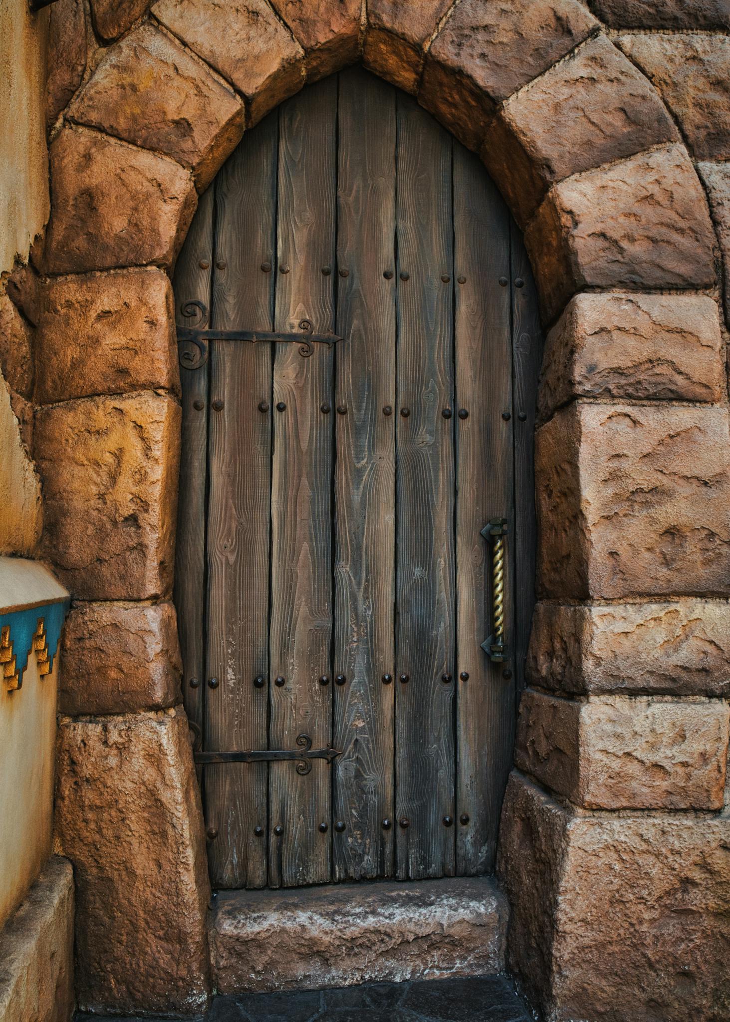 A rustic wooden door set within a stone archway at Tokyo DisneySea.