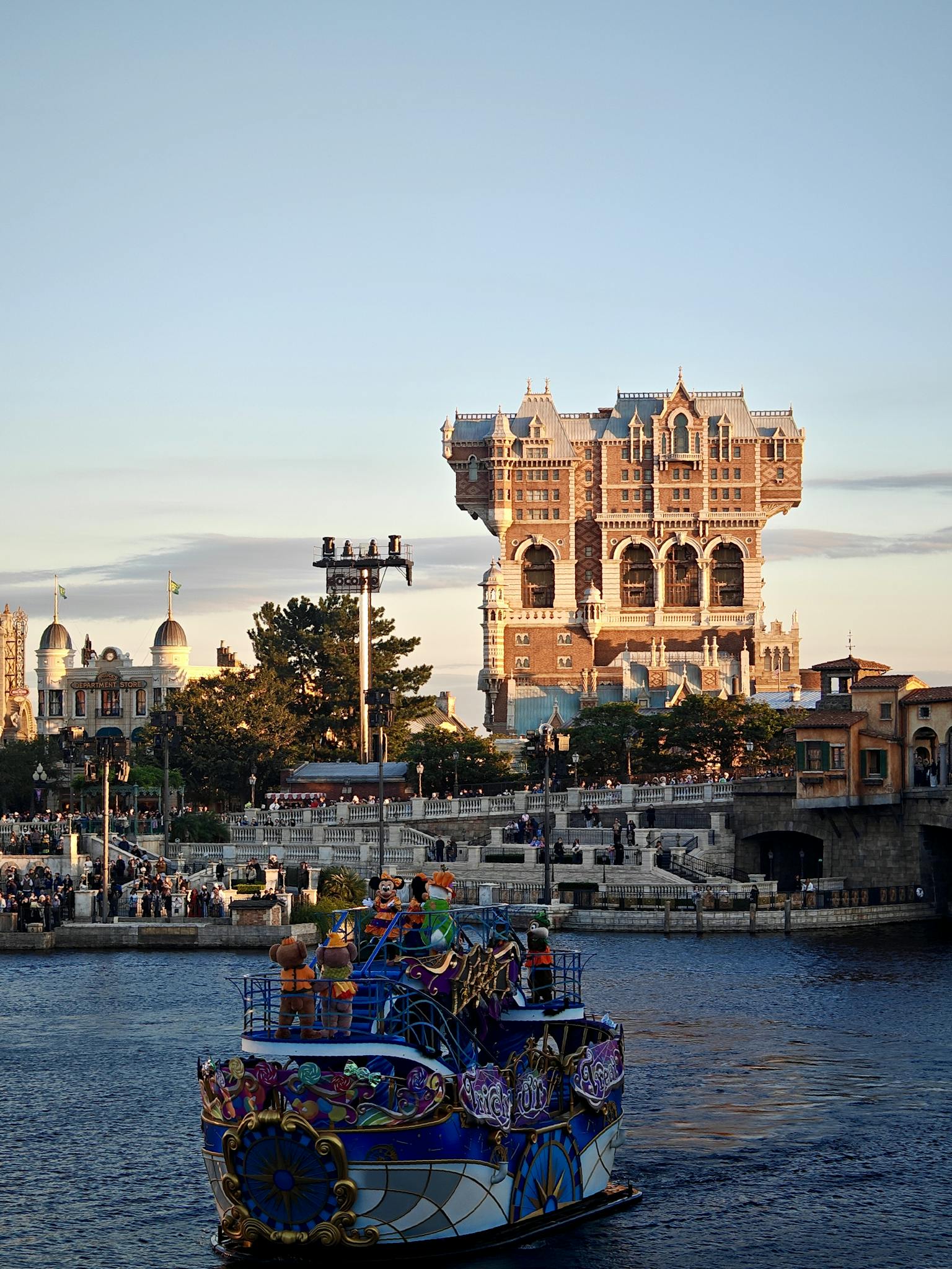 A vibrant boat sails near the iconic Tower of Terror at DisneySea during daytime.